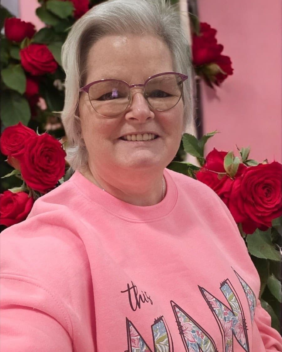 Kathy Noblin, Florida-commissioned notary, smiling in front of red roses